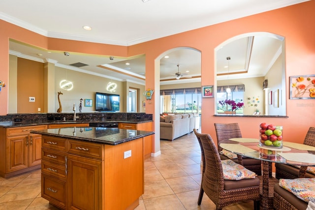 kitchen with ceiling fan, pendant lighting, dark stone counters, and kitchen peninsula