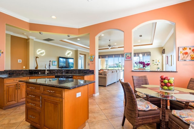 kitchen featuring brown cabinets, a kitchen island, ornamental molding, and a raised ceiling