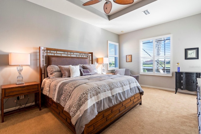 bedroom with a tray ceiling, light carpet, baseboards, visible vents, and ceiling fan