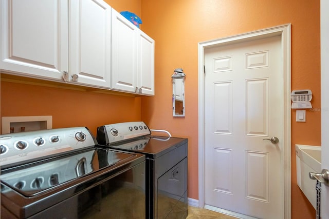 clothes washing area featuring light tile patterned floors, cabinet space, and washing machine and dryer