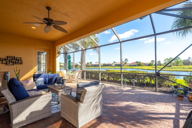 view of patio with a lanai, an outdoor hangout area, a water view, and ceiling fan