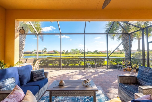 view of patio featuring glass enclosure, a water view, ceiling fan, and outdoor lounge area