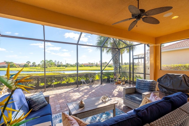 view of patio featuring glass enclosure, a water view, an outdoor hangout area, and ceiling fan