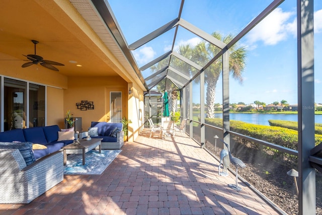 sunroom with ceiling fan and a water view