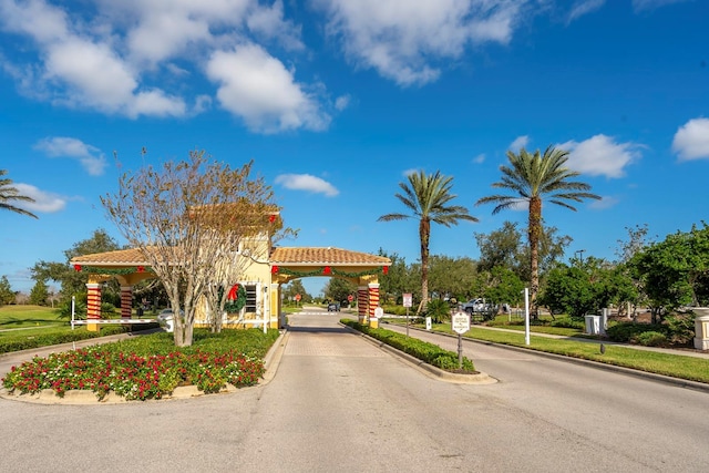view of road featuring sidewalks, a gated entry, and curbs