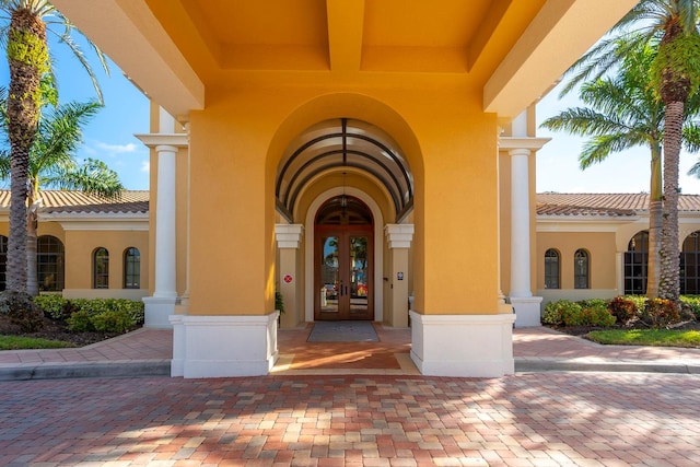 entrance to property with french doors, a tiled roof, and stucco siding