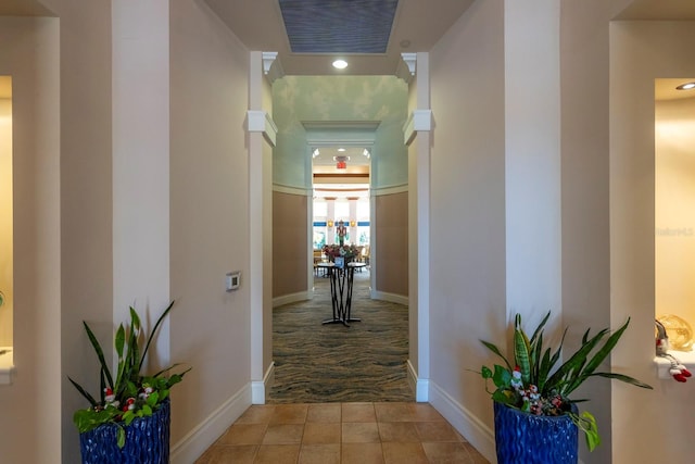 hall featuring baseboards, visible vents, and light tile patterned floors