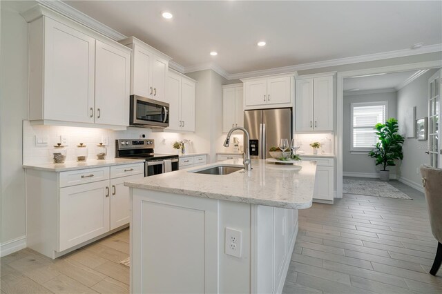 kitchen featuring an island with sink, sink, stainless steel appliances, and white cabinets