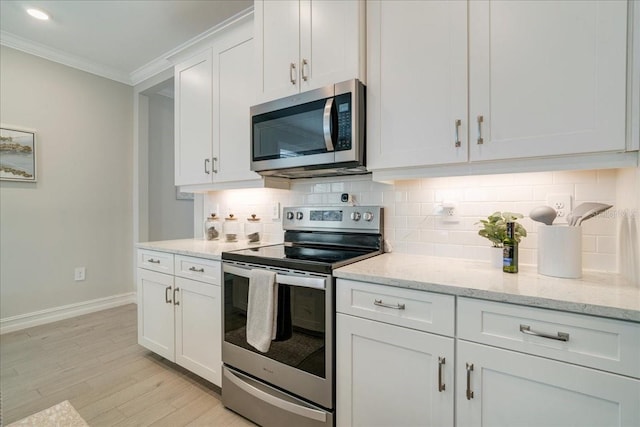 kitchen with white cabinetry, stainless steel appliances, light stone countertops, crown molding, and light hardwood / wood-style floors