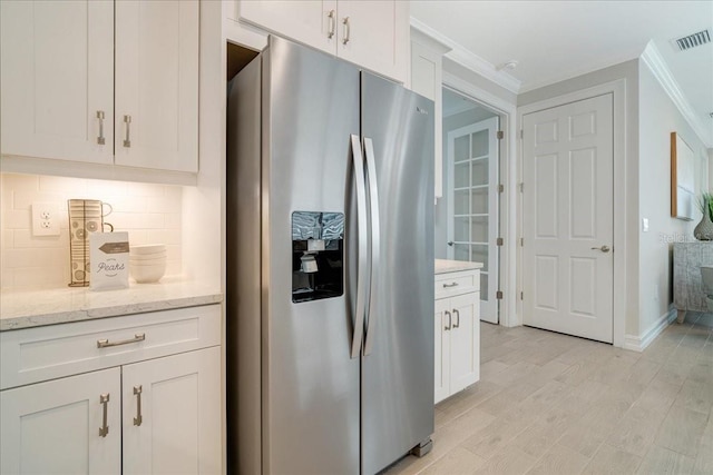 kitchen with white cabinets, ornamental molding, stainless steel fridge with ice dispenser, light stone countertops, and decorative backsplash