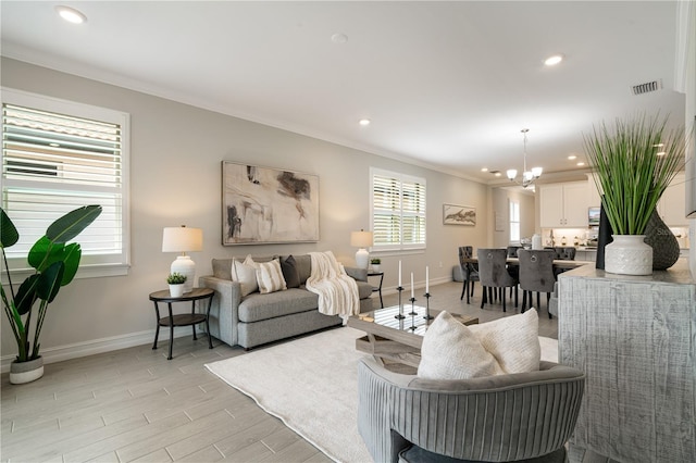 living room featuring light wood-type flooring, crown molding, and a notable chandelier