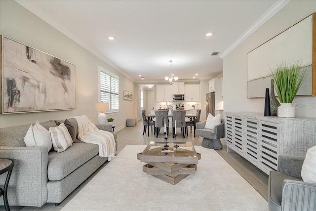 living room with a notable chandelier, light wood-type flooring, and ornamental molding