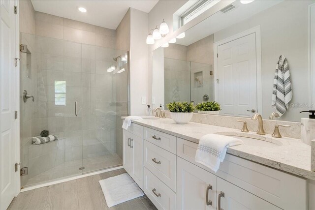 bathroom with a healthy amount of sunlight, vanity, a shower with door, and hardwood / wood-style floors