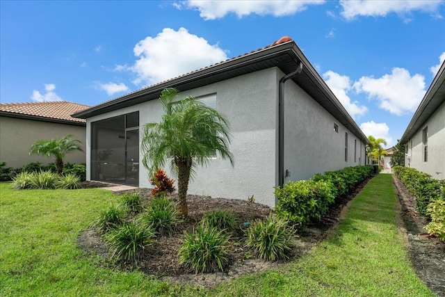 view of side of home featuring a sunroom and a yard