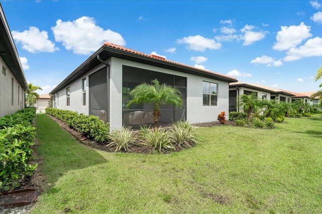 view of property exterior featuring a sunroom and a yard