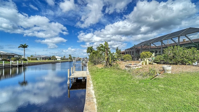 dock area with a water view, a lanai, and a lawn