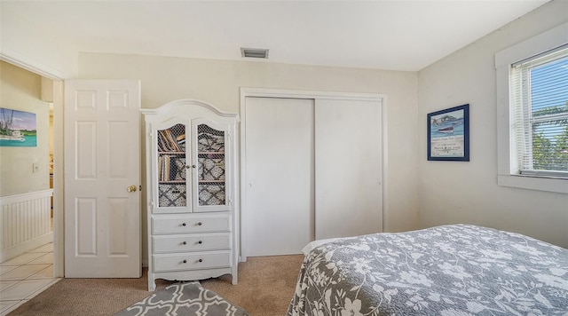 bedroom featuring light carpet and a closet