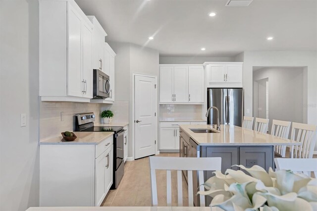 kitchen with white cabinets, a kitchen island with sink, appliances with stainless steel finishes, and sink