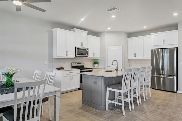 kitchen with appliances with stainless steel finishes, white cabinetry, sink, and ceiling fan