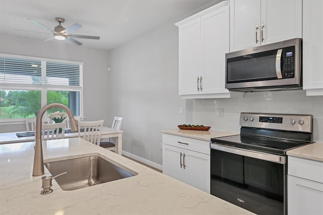 kitchen with ceiling fan, white cabinets, sink, stainless steel appliances, and light stone countertops