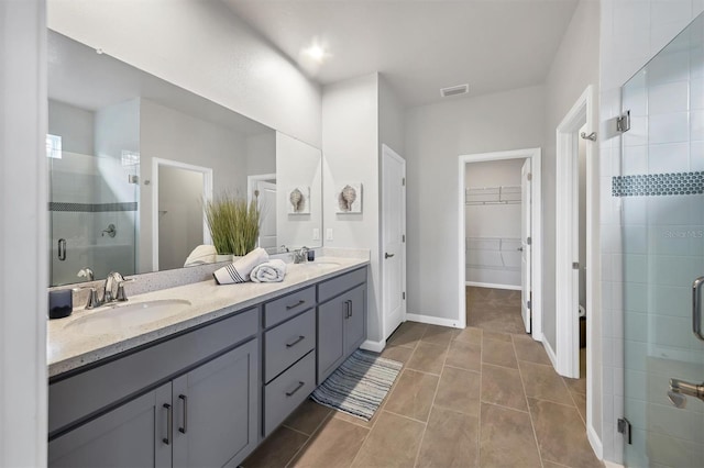 bathroom with walk in shower, vanity, and tile patterned flooring