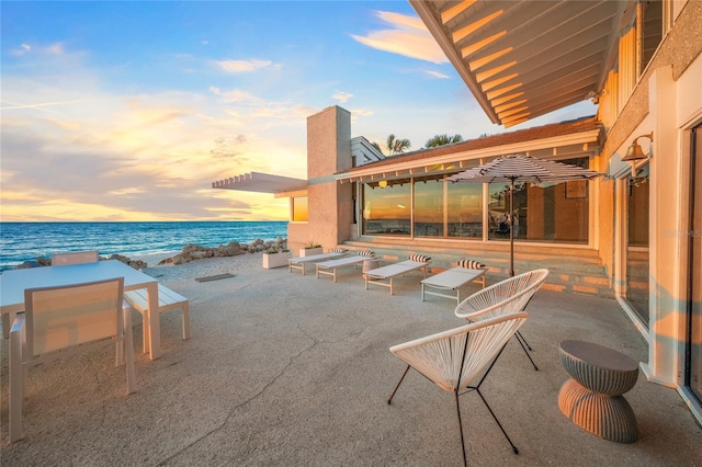 patio terrace at dusk with a water view and a beach view