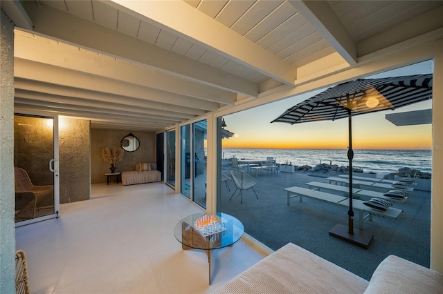 patio terrace at dusk featuring a water view and a view of the beach