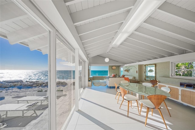 sunroom with a beach view, lofted ceiling with beams, and a water view