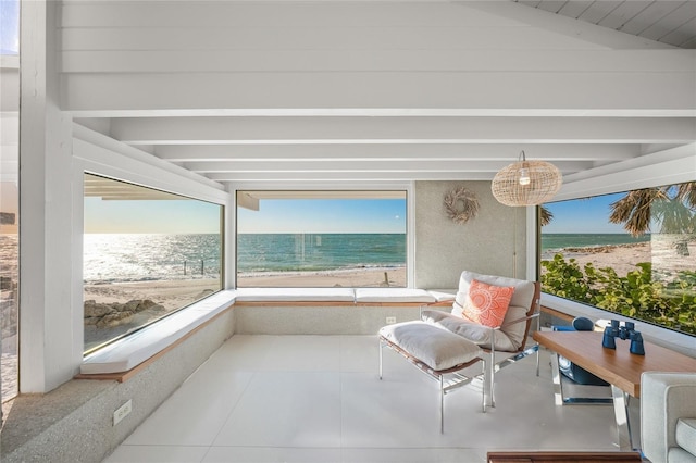 sunroom / solarium with a water view, lofted ceiling, and a view of the beach