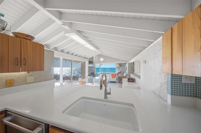 kitchen with dishwashing machine, sink, and lofted ceiling with beams