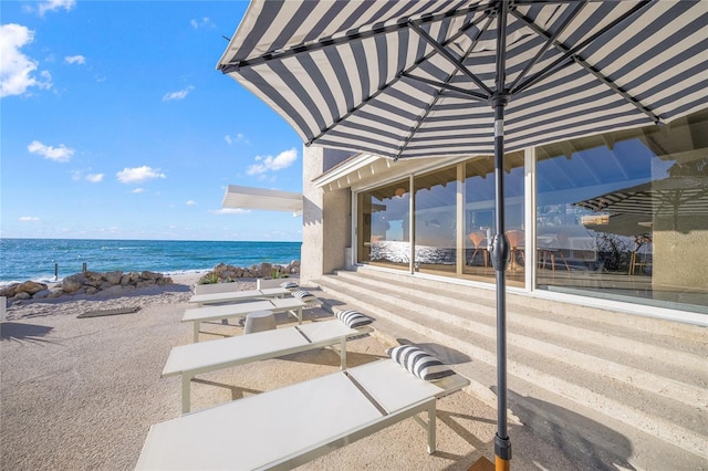 view of patio / terrace featuring a water view and a beach view