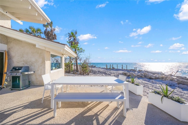 view of patio with area for grilling and a water view