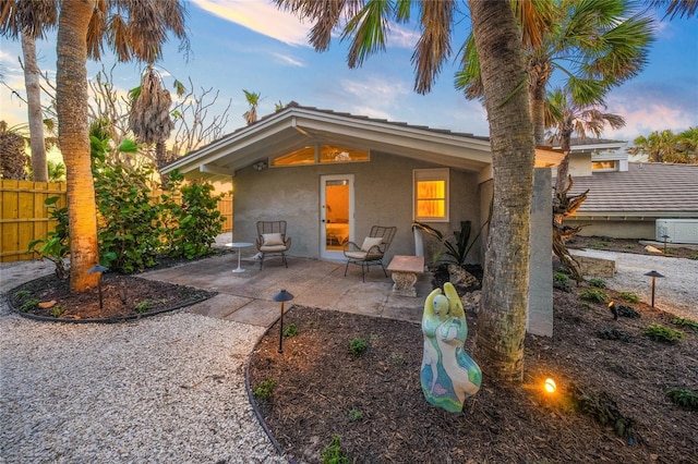 back house at dusk with a patio area