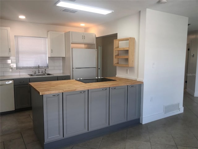 kitchen with white appliances, butcher block countertops, sink, and backsplash