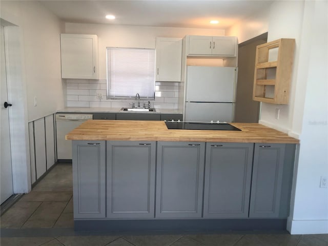 kitchen featuring white appliances, butcher block countertops, sink, and white cabinetry