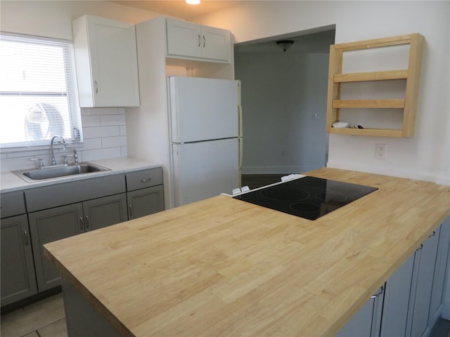 kitchen with gray cabinetry, decorative backsplash, sink, and white refrigerator