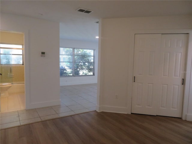 unfurnished bedroom featuring multiple windows, light wood-type flooring, and a closet