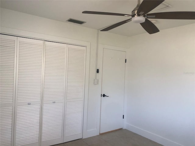 unfurnished bedroom with tile patterned flooring, ceiling fan, and a closet