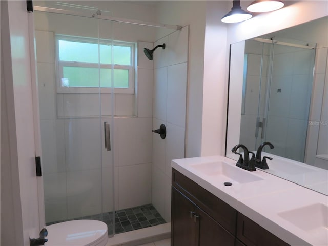 bathroom featuring a shower with shower door, vanity, and toilet