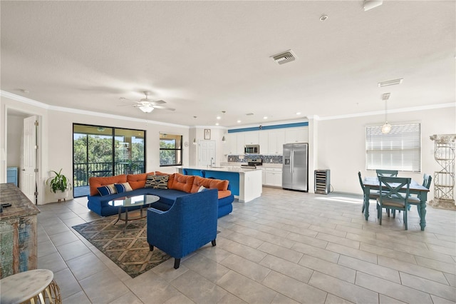 tiled living room featuring a textured ceiling, ornamental molding, sink, and ceiling fan