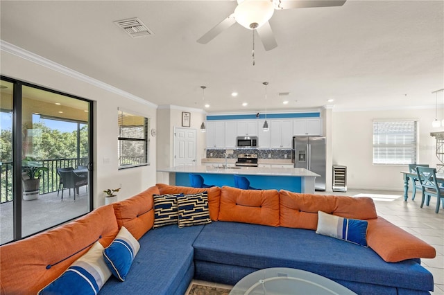 tiled living room featuring ceiling fan, ornamental molding, plenty of natural light, and sink