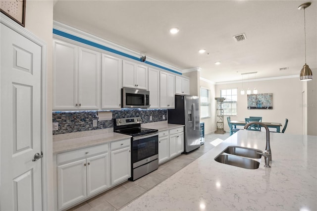 kitchen with light stone counters, pendant lighting, white cabinets, stainless steel appliances, and crown molding