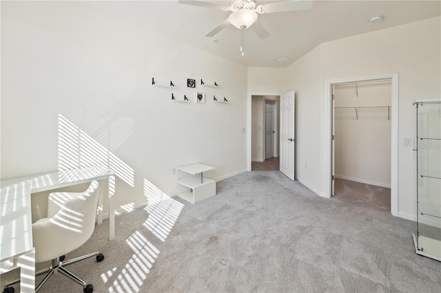 unfurnished bedroom featuring light carpet, a closet, a spacious closet, and ceiling fan