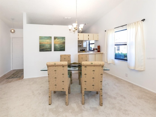 carpeted dining area featuring vaulted ceiling and a chandelier