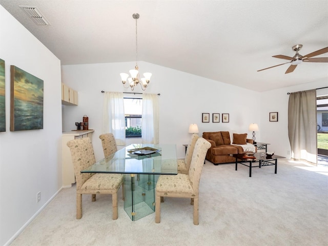 carpeted dining area featuring ceiling fan with notable chandelier and vaulted ceiling