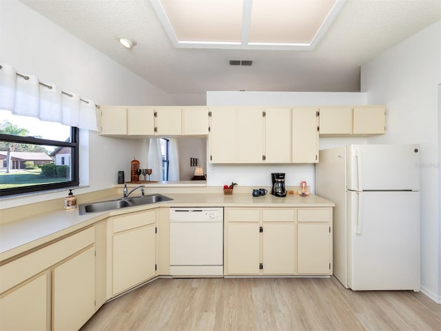 kitchen with light hardwood / wood-style floors, cream cabinetry, sink, and white appliances