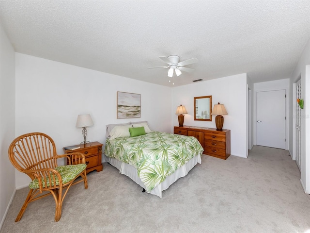 bedroom featuring a textured ceiling, light carpet, and ceiling fan