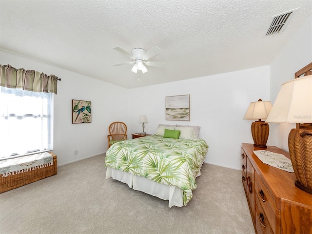 carpeted bedroom with ceiling fan and a textured ceiling