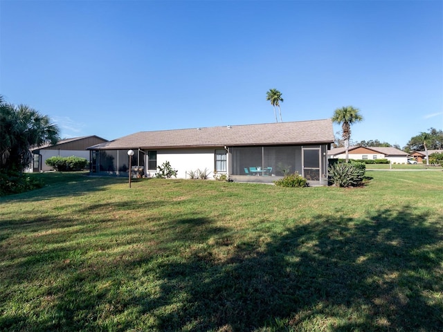 back of property featuring a lawn and a sunroom