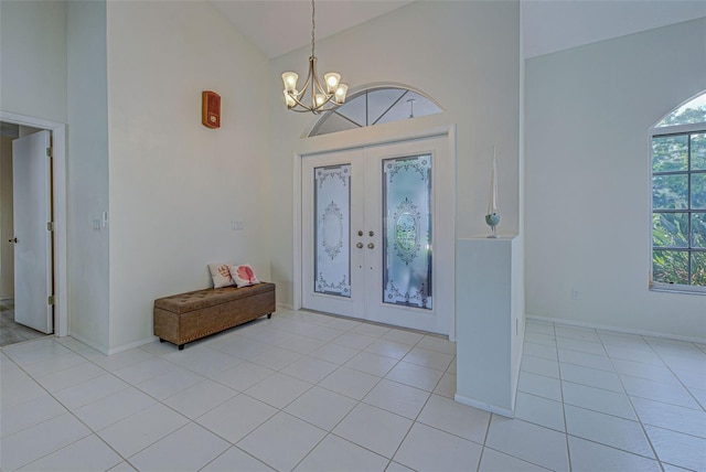 tiled entrance foyer featuring french doors, high vaulted ceiling, and a chandelier